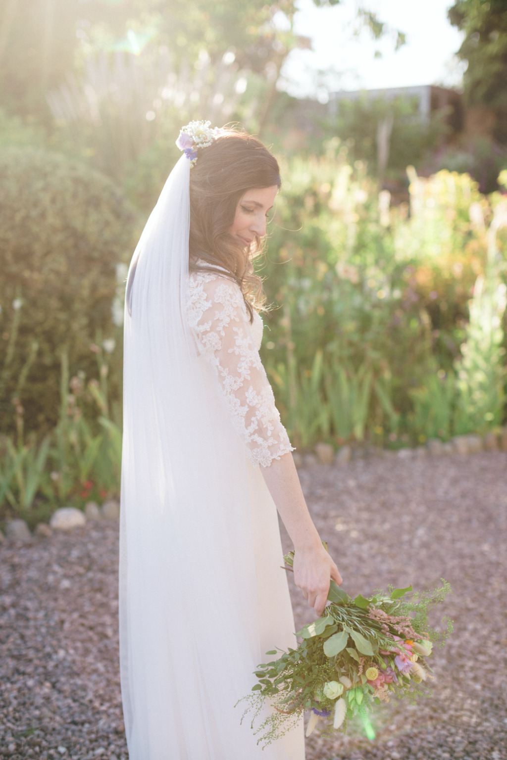Bride wearing veil and bridal gown sunny summer shot bouquet of flowers