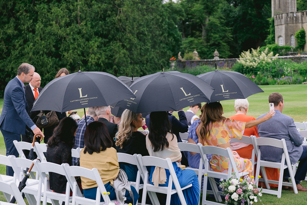 it starts to rain on guests as they hold up black umbrellas