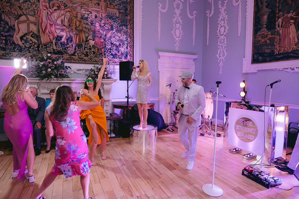Guests dance orange pink dresses and wedding guitarist singer band